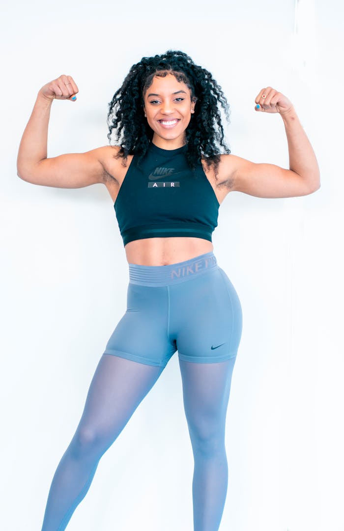 Strong woman posing indoors, showcasing fitness and strength with a confident smile.
