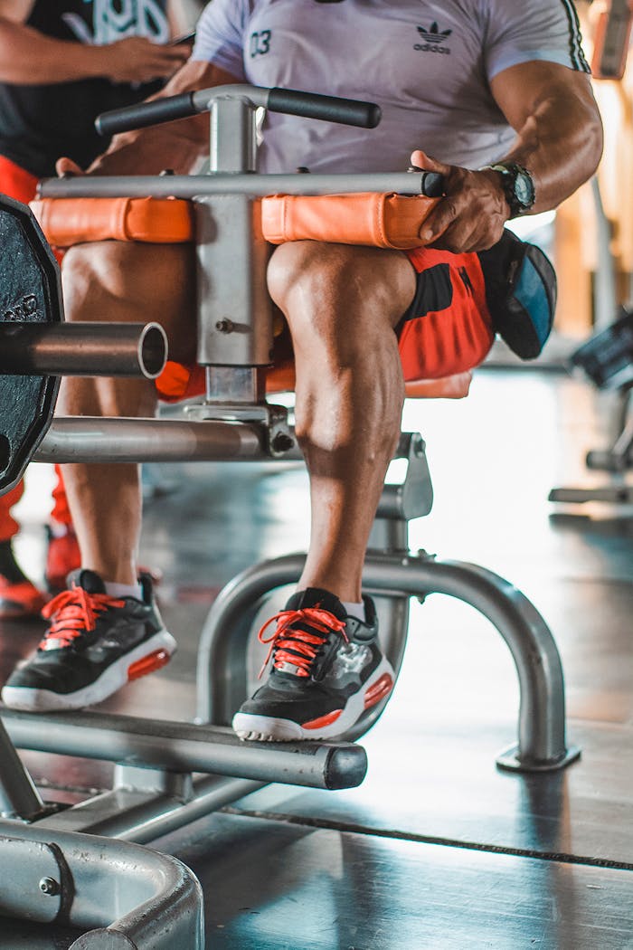 Adult man working out on a leg exercise machine in a modern indoor gym.